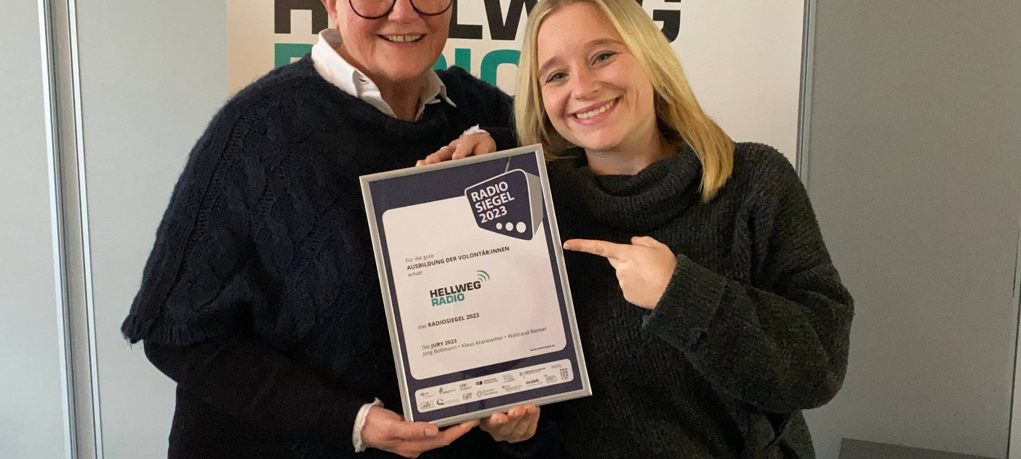 Chefredakteurin Ruth Heinemann und Volontärin Franzi Reinl halten das Radiosiegel in ihren Händen.