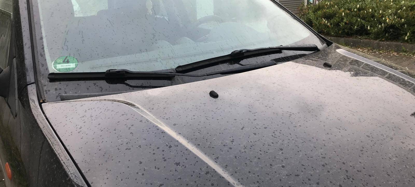 Ein schwarzes Auto auf dem sich Saharastaub abgelegt hat.