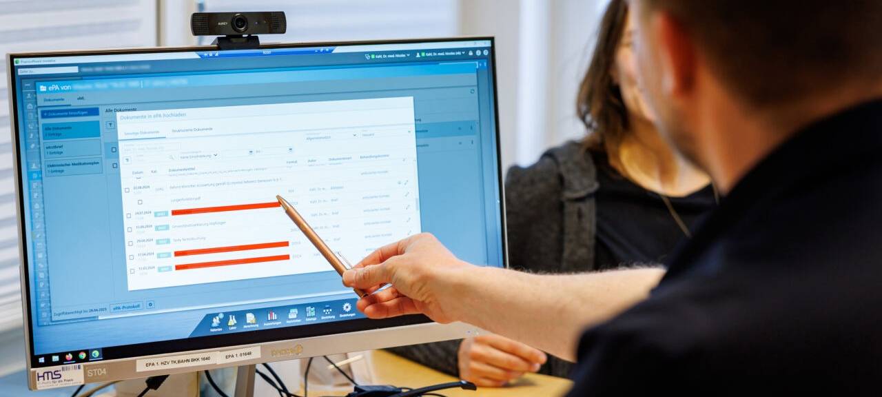 Ein Hausarzt lädt in seiner Praxis Dokumente in eine elektronische Patientenakte