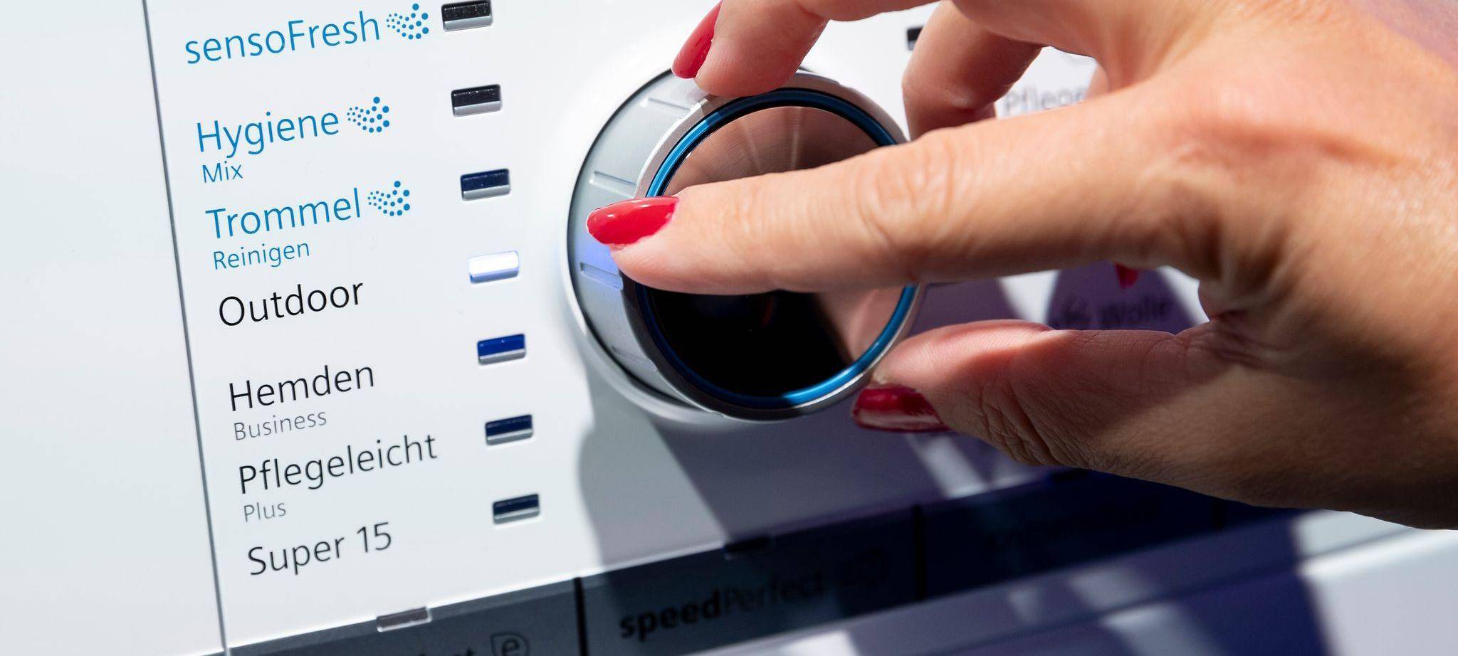 Eine Frau dreht einen Knopf an einer Waschmaschine