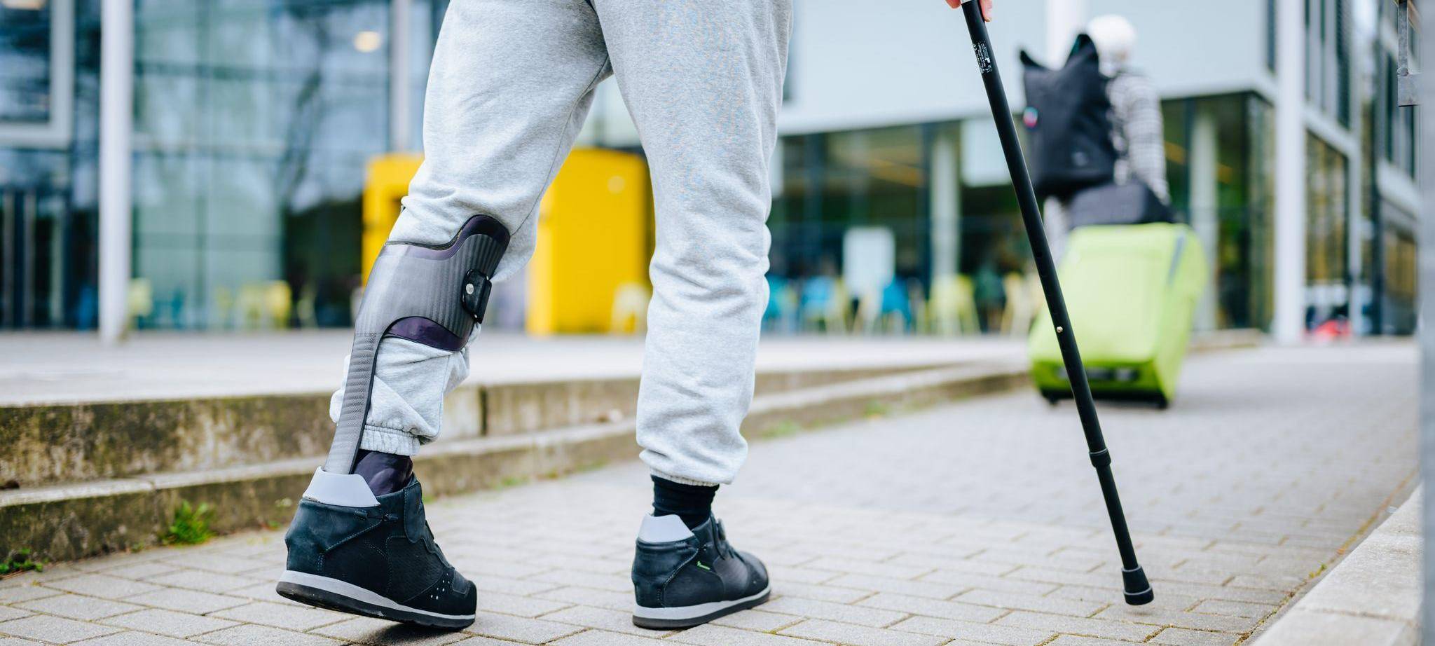 Ein Mann läuft mit einer Gehhilfe auf der Straße