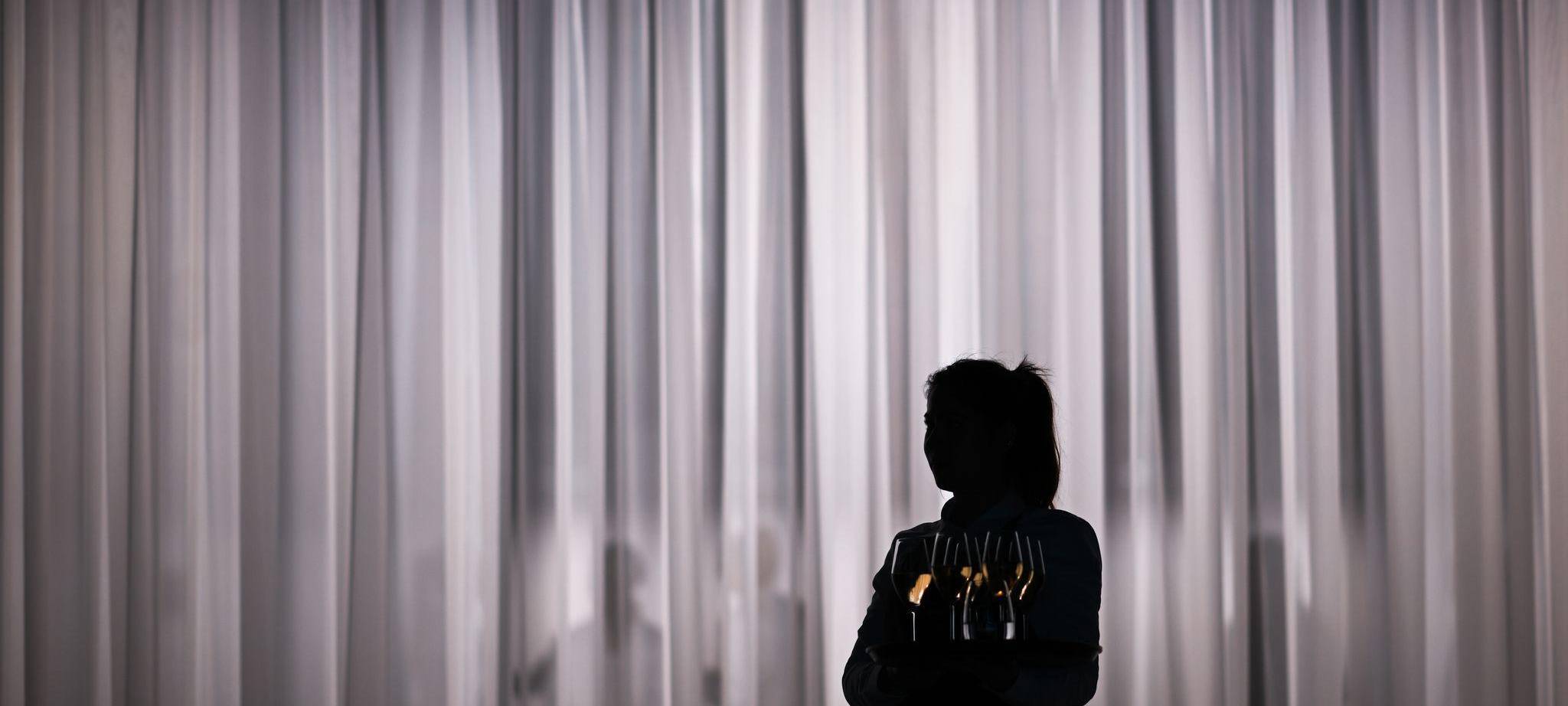 Eine Servicemitarbeiterin steht vor einem hellen Vorhang