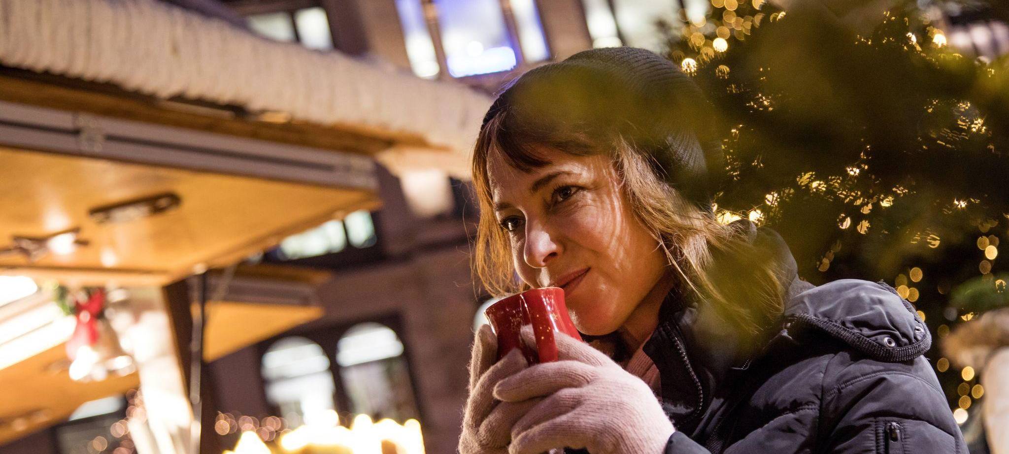 Frau trinkt auf dem Weihnachstmarkt ein Heissgetränk