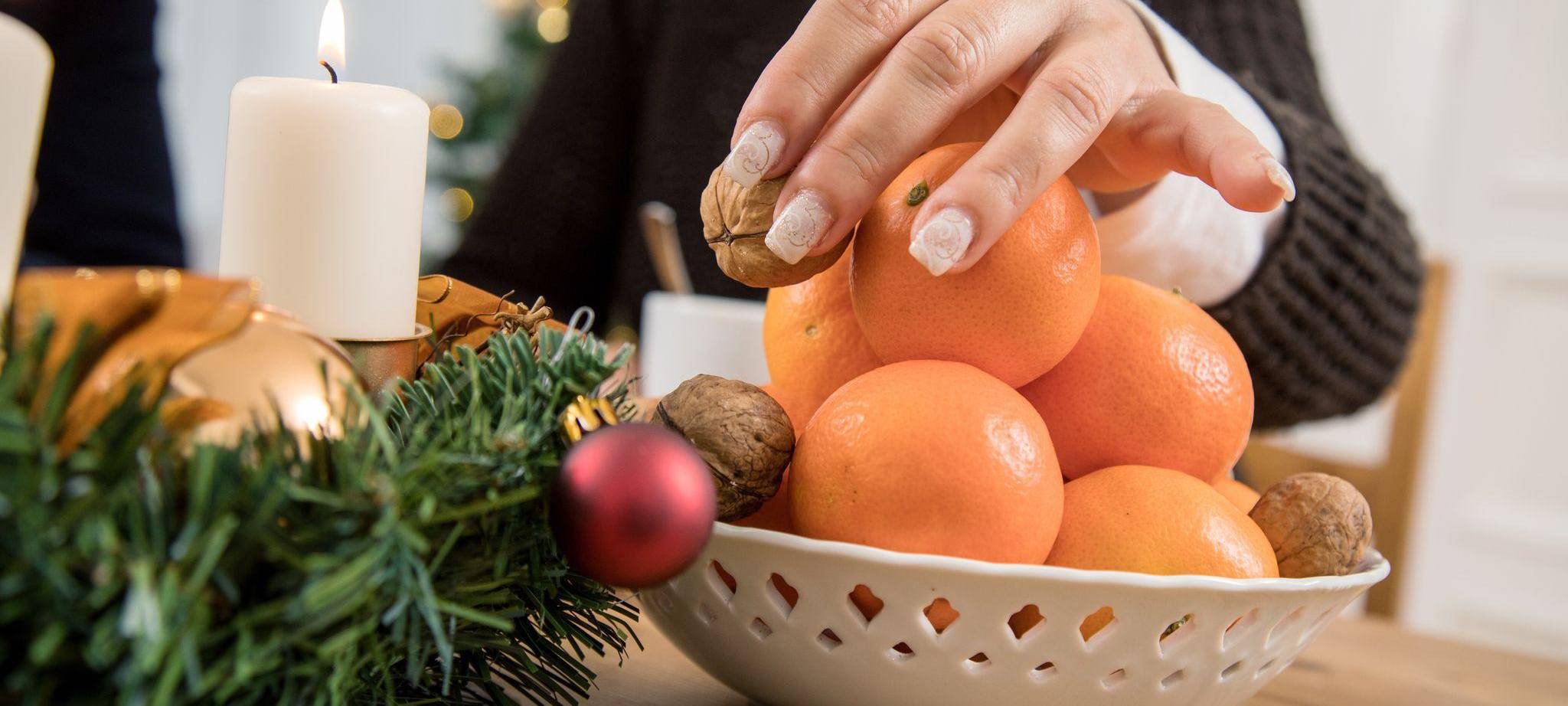 Frau greift nach einer Walnuss in einer Obstschale