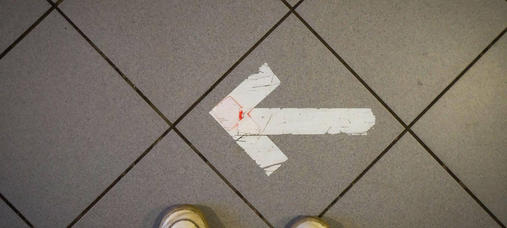 Ein Pfeil aus Klebeband ist auf einem Fußboden zu sehen