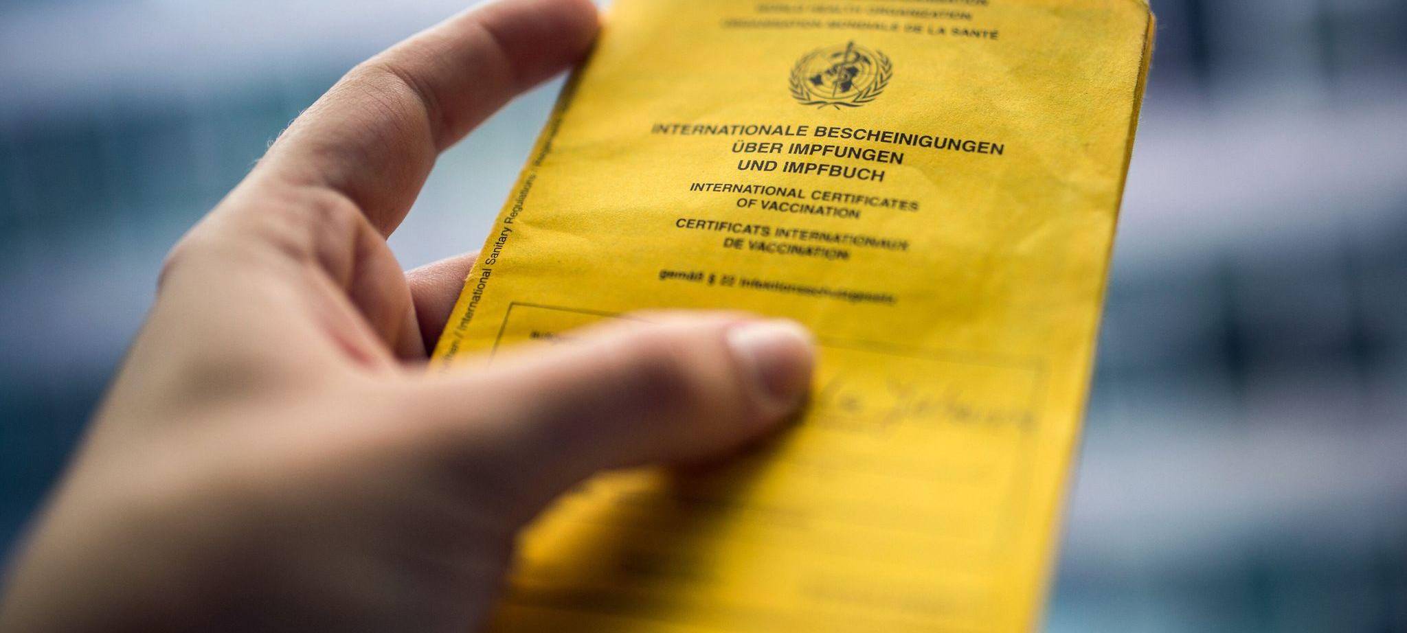 Person hält einen Impfausweis in der Hand