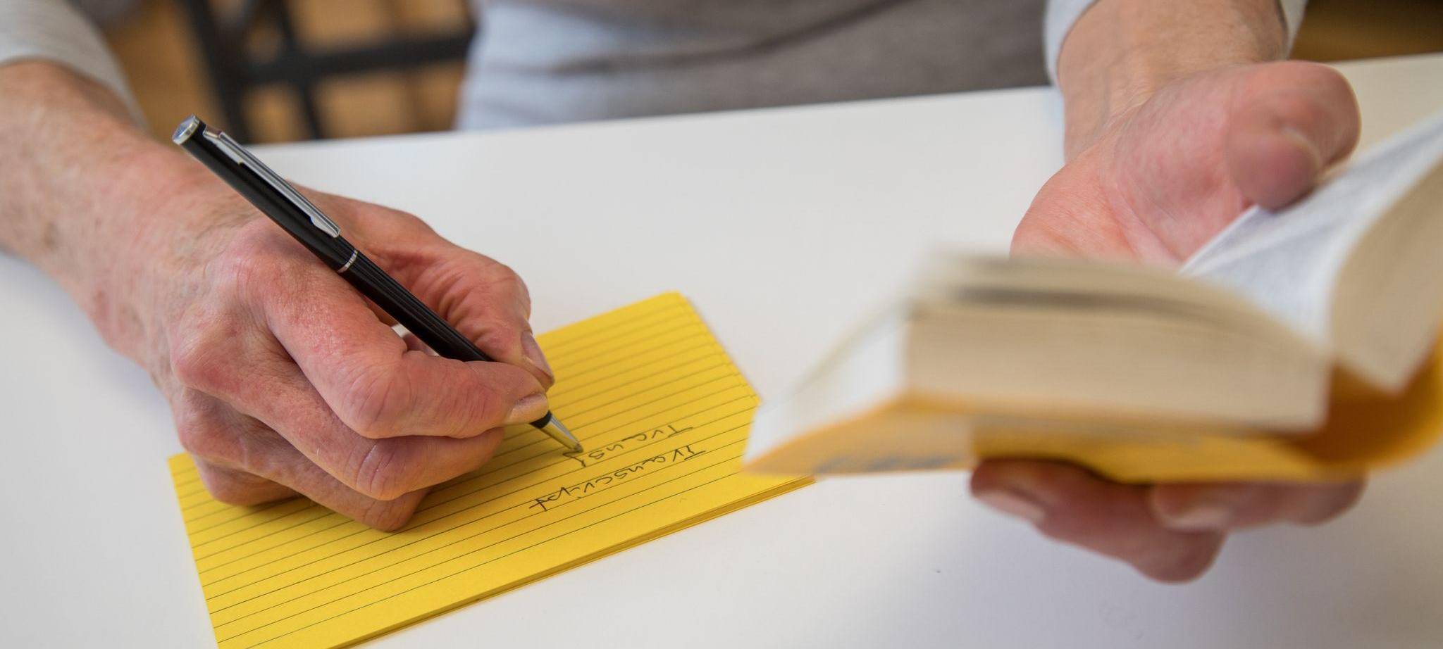 Eine Frau notiert Vokabeln aus einem Woerterbuch heraus