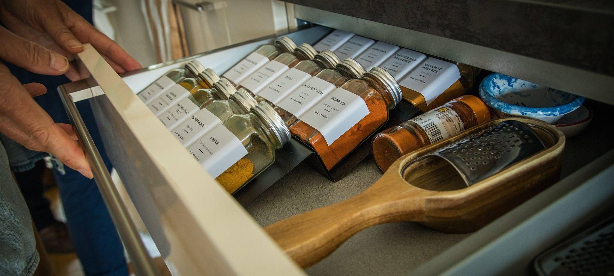 Eine Person öffnet eine Gewürzschublade in einer Küche