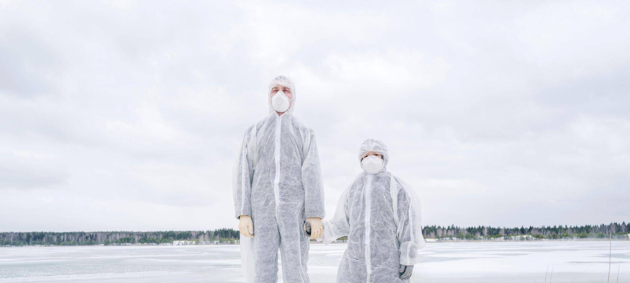 Ein Mann und ein Kind in Schutzanzügen halten Händchen