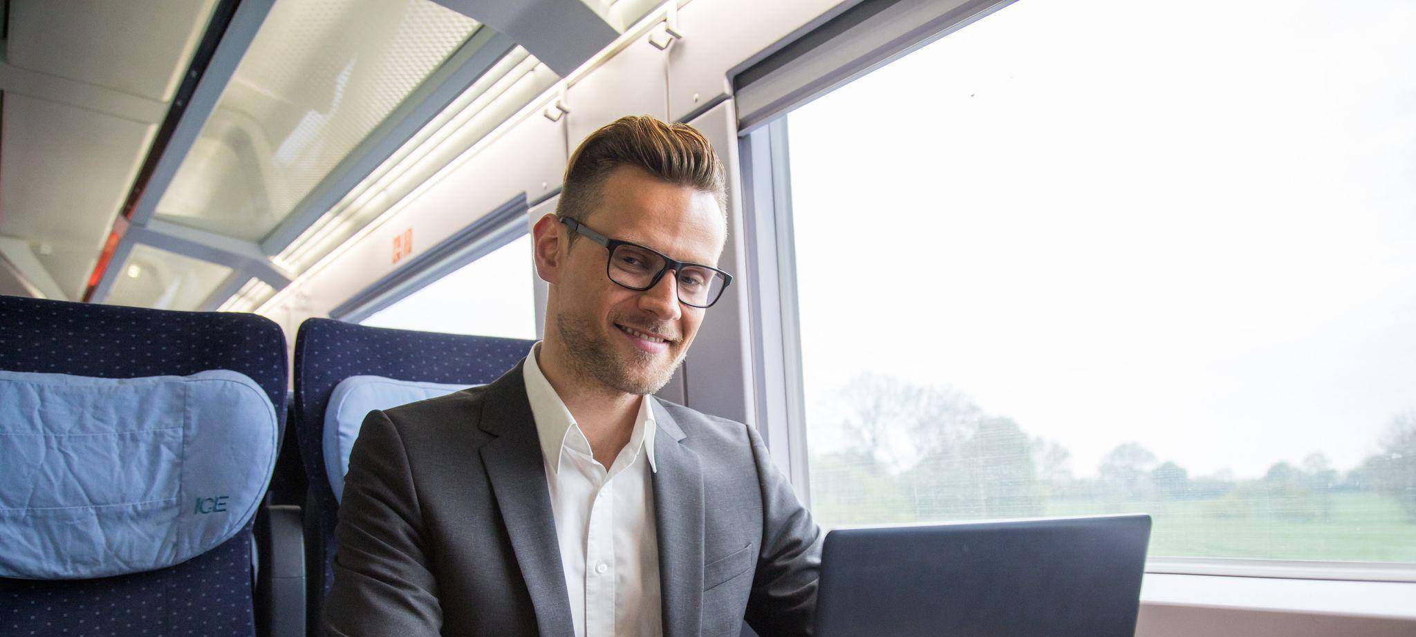 Ein mann arbeitet in einem Zug an einem Laptop