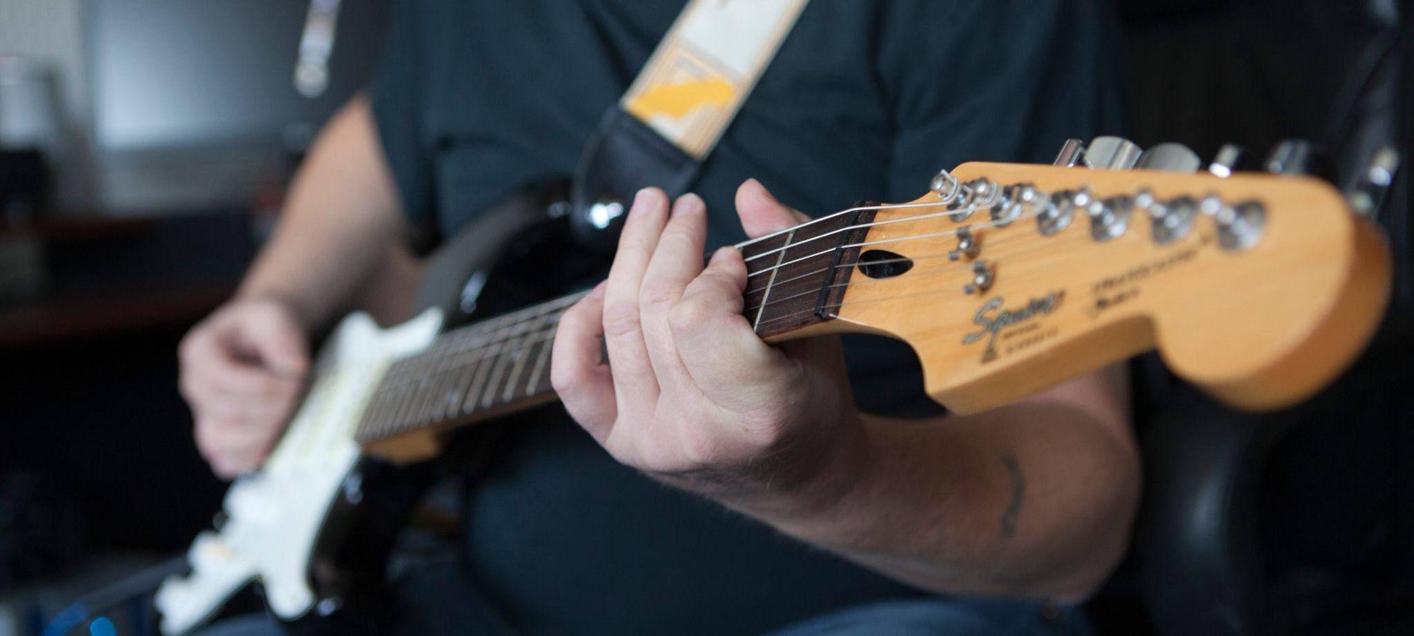 Mann spielt auf einer E-Gitarre