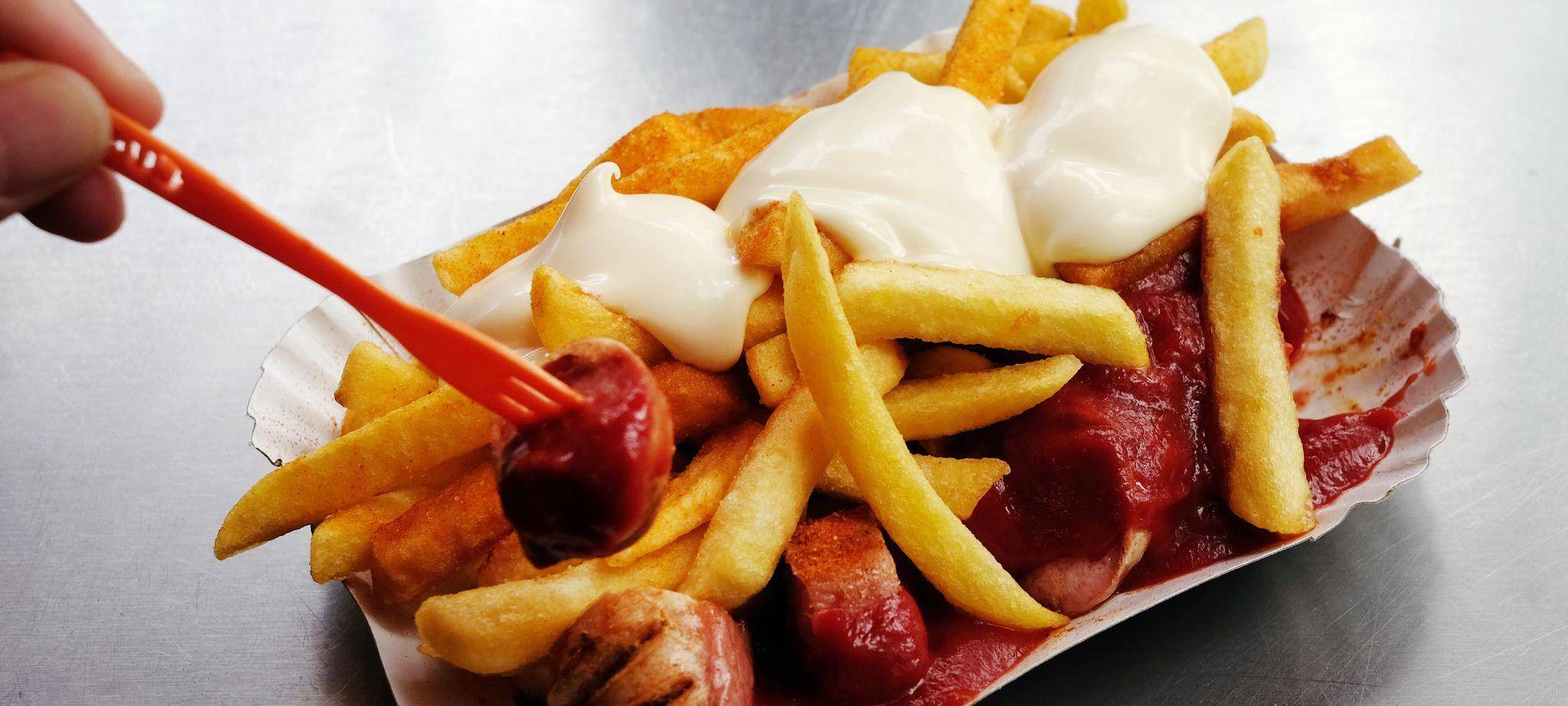 Eine Currywurst mit Pommes und Mayo