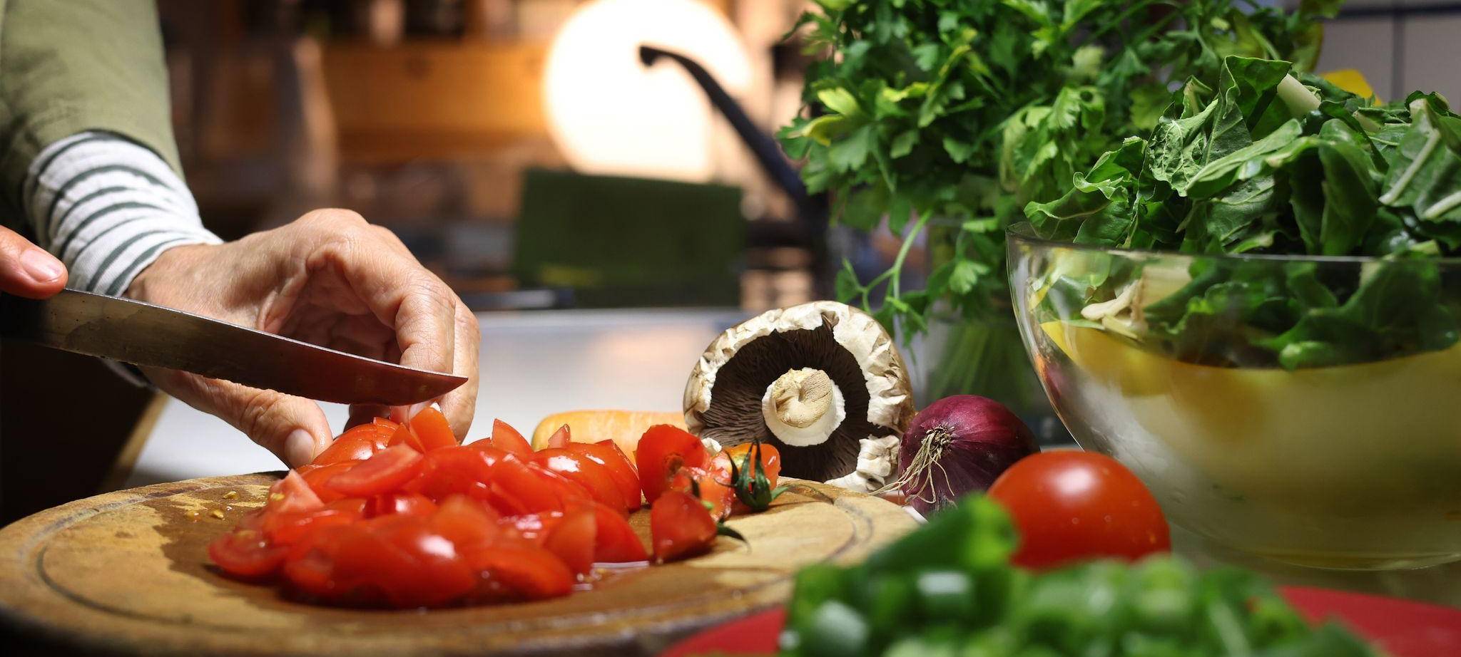 Eine Frau bereitet beim Kochen das Gemüse vor