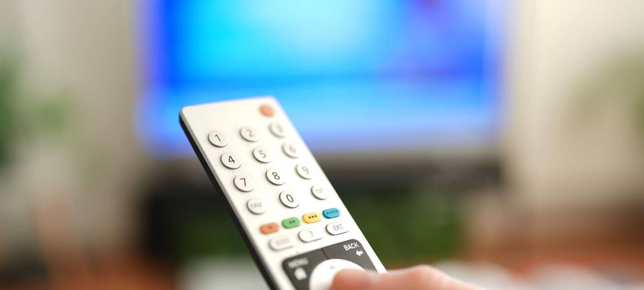 Ein Mann drückt einen Knopf auf einer TV-Fernbedienung