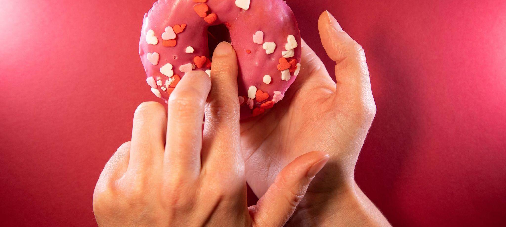 Ein Finger wird in einen Donut gesteckt