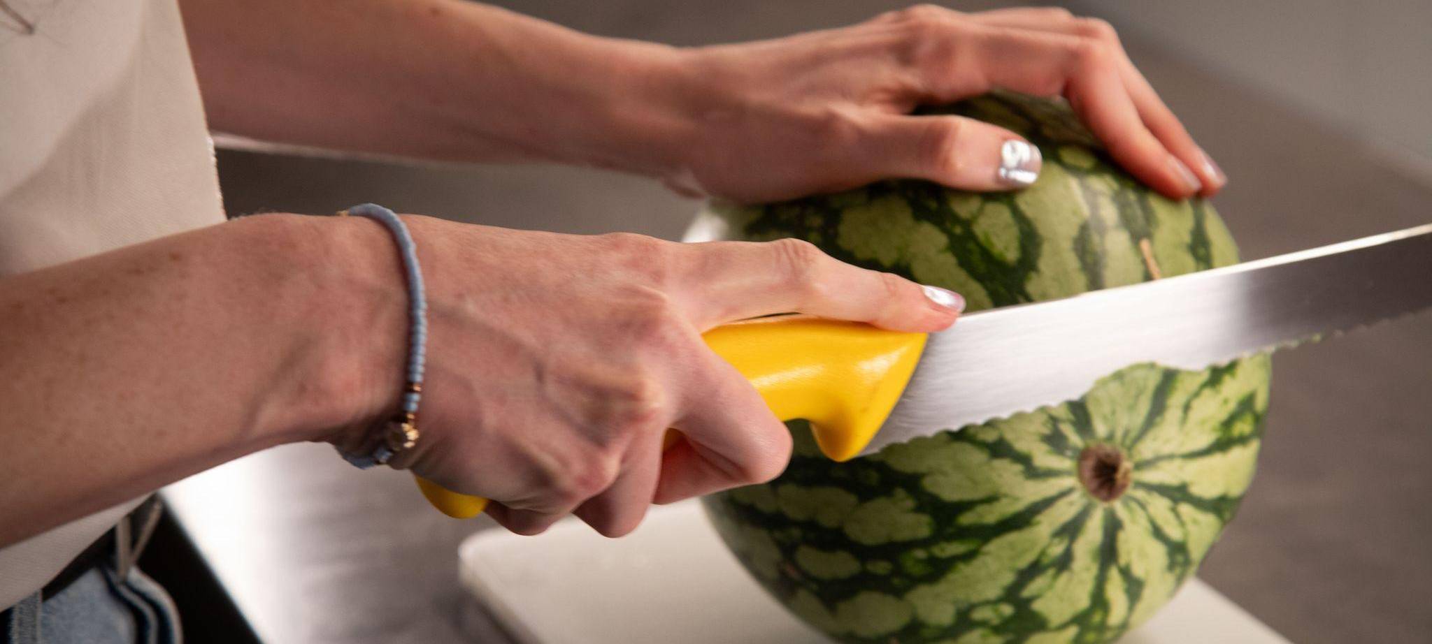 Frau schneidet eine Wassermelone auf