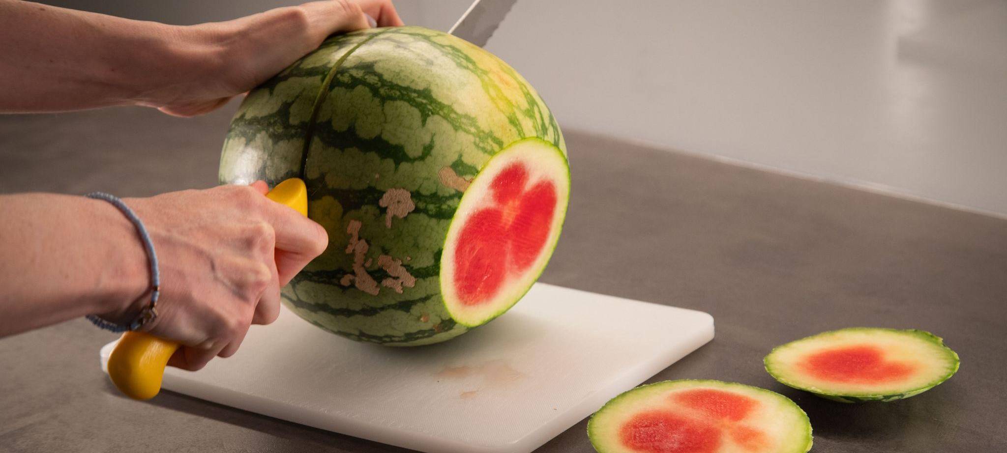 Frau schneidet eine Wassermelone auf