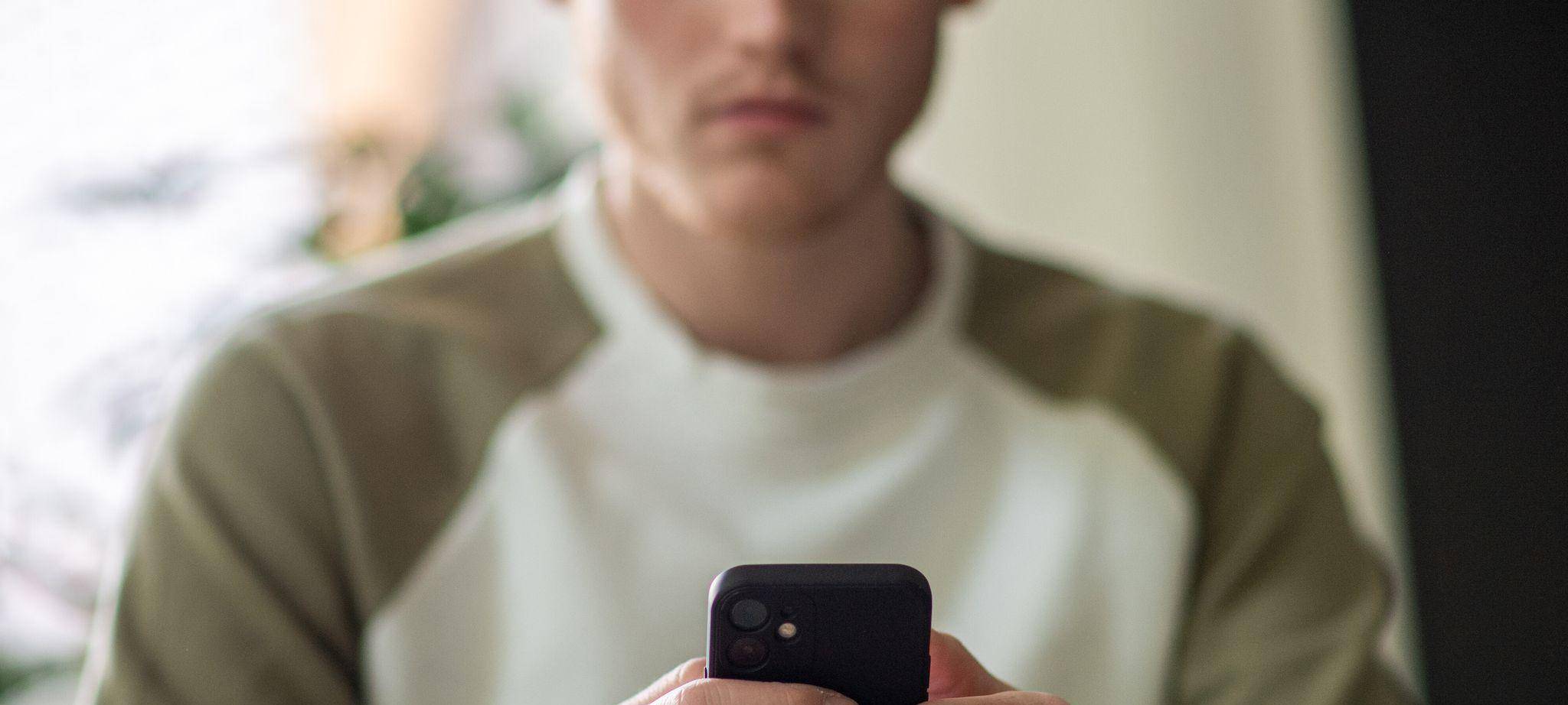 Ein junger Mann tippt auf seinem Handy