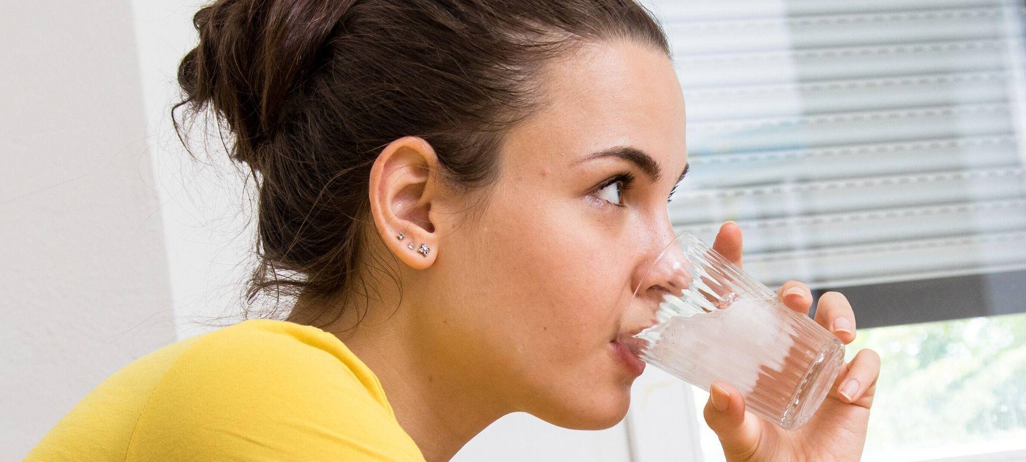 Eine Frau trinkt ein Glas Wasser