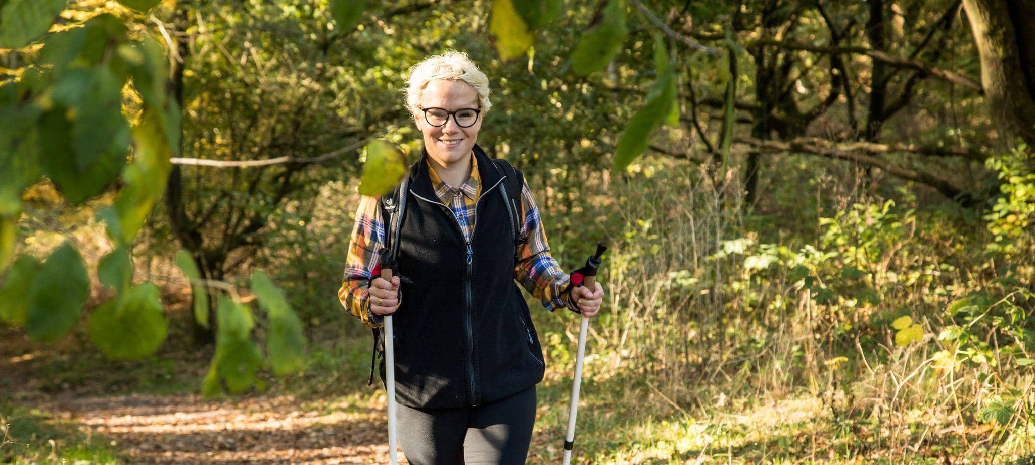 Eine Frau wandert mit Wanderstöcken durch den Wald