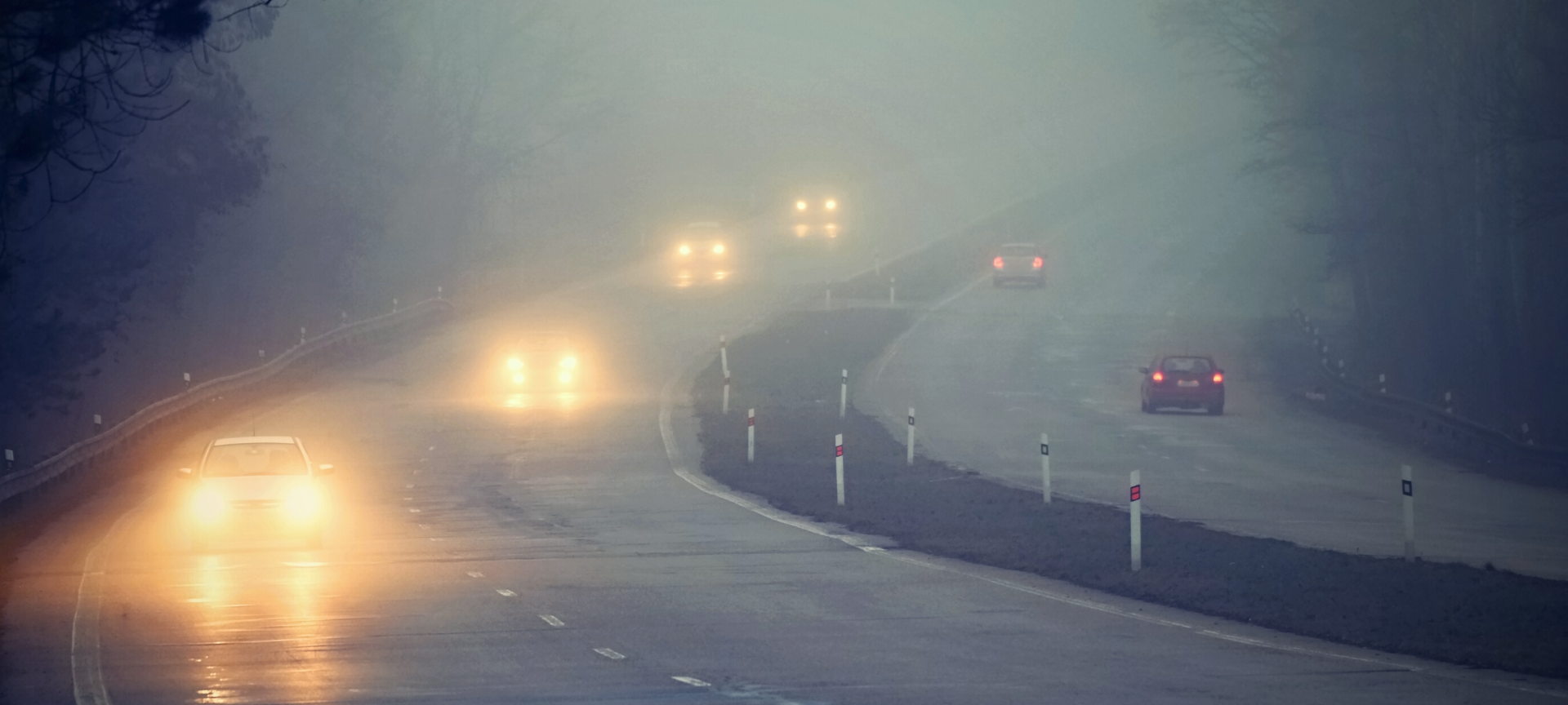 Autos unterwegs auf einer nebeligen, glatten Straße.