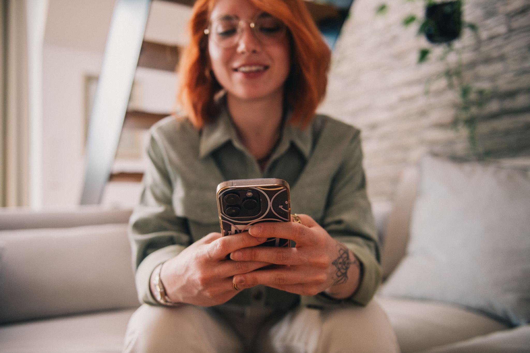 Eine Frau sitzt mit Smartphone auf einer Couch