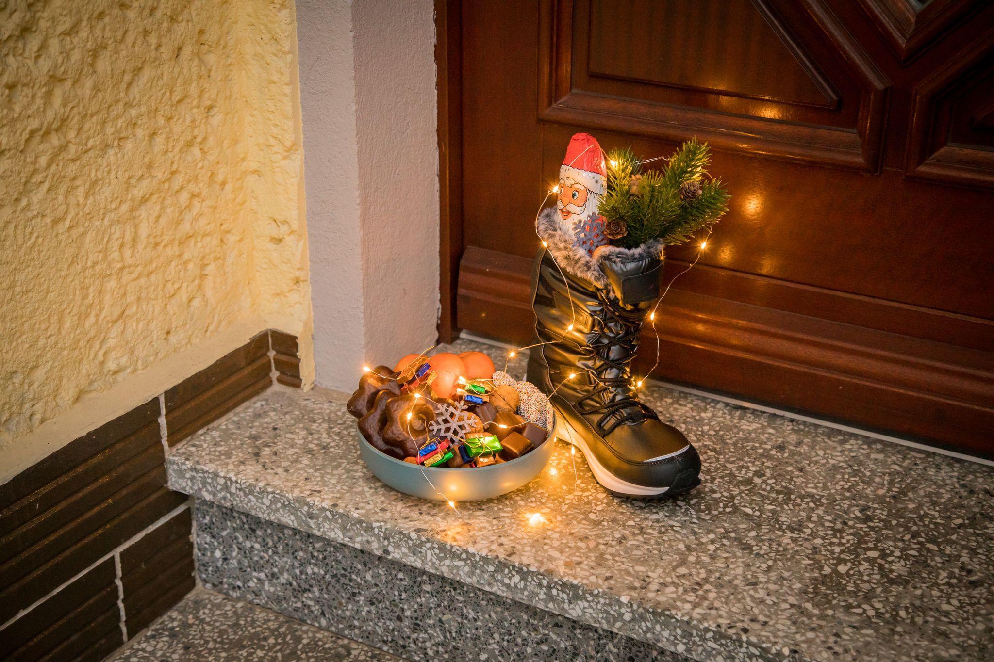 Mit Süßgkeiten gefüllter Stiefel steht zu Nikolaus vor einer Tür